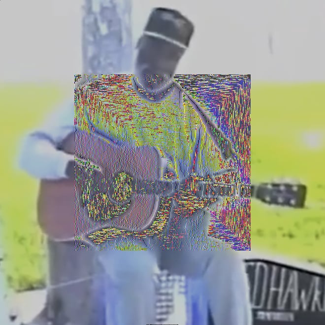 A medium VHS-recorded shot of Ted Hawkins sitting on a makeshift stool on the Venice Beach boardwalk, longsleeve shirt, ballcap, acoustic guitar in hand. The cropped letters 'D HAWKI' — part of 'TED HAWKINS' — can be seen in tall hand-painted capitals on a guitar case on the right side of the image on the ground. The image is sunlit high contrast with a lot of white and green. In the center is a square covering half the image with intense red, blue, yellow, and green noise.